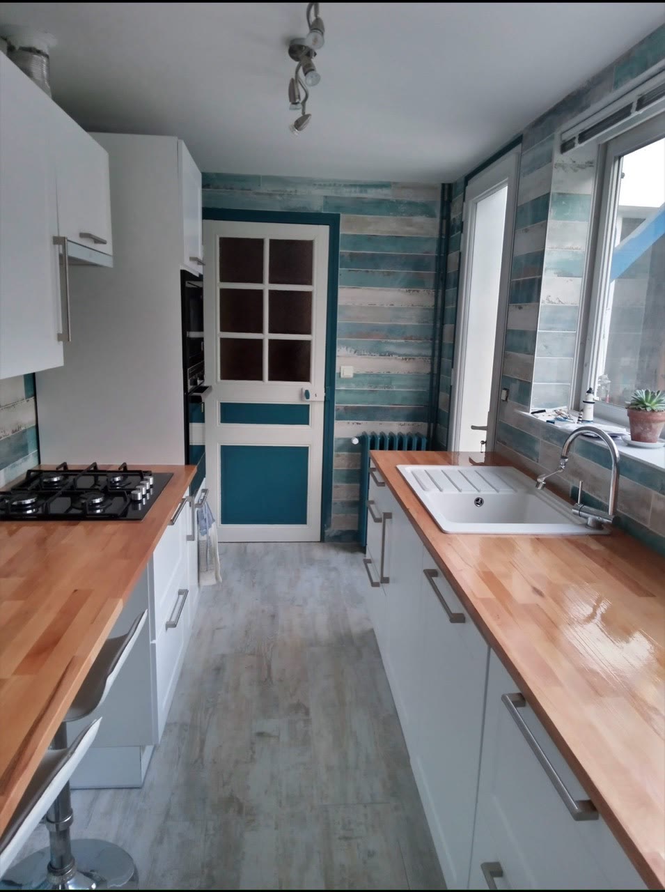 Aménagement de cuisine avec verrière, plan de travail et finitions murales